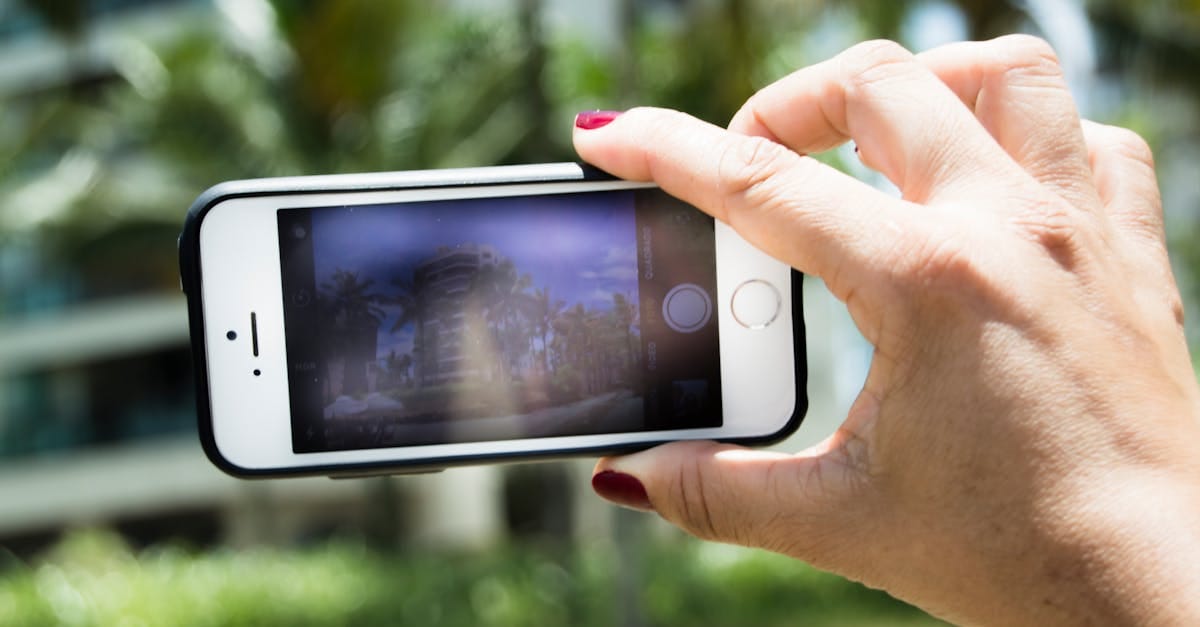 A hand holding a smartphone capturing a blurred outdoor background, highlighting phone photography.